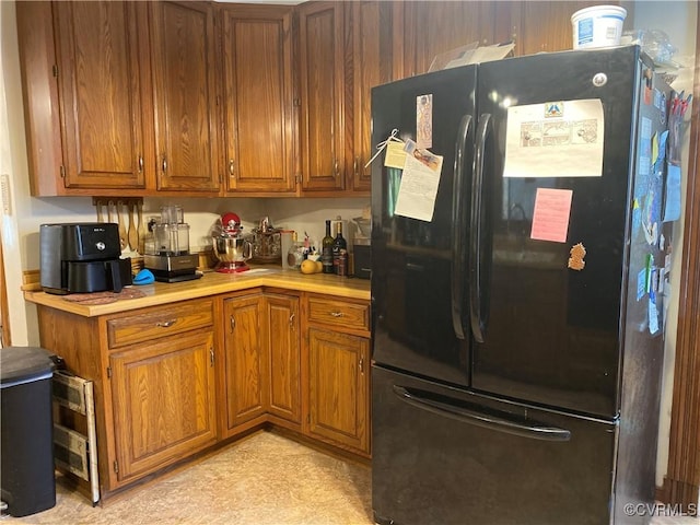 kitchen featuring brown cabinetry, freestanding refrigerator, and light countertops
