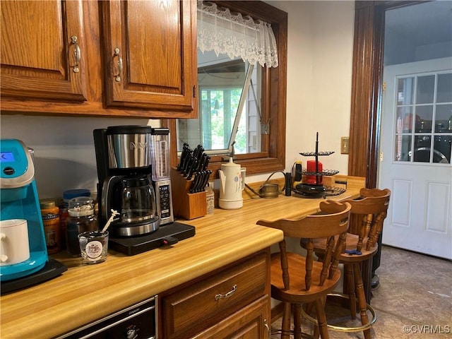 kitchen featuring brown cabinets, wooden counters, and dishwashing machine
