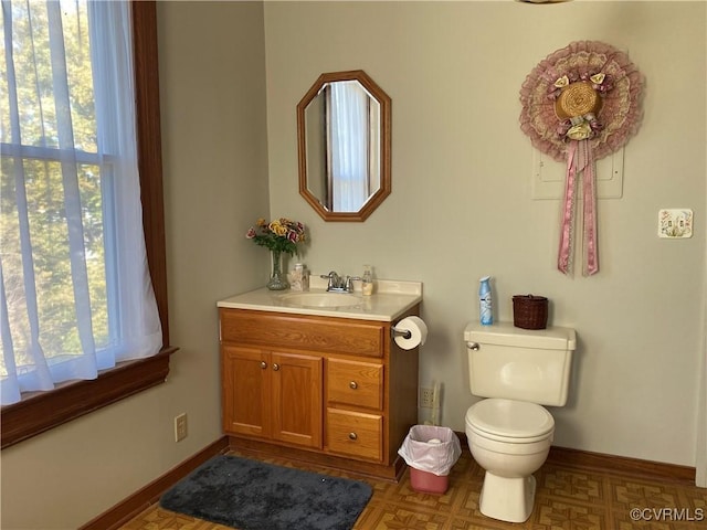 bathroom with toilet, vanity, and baseboards