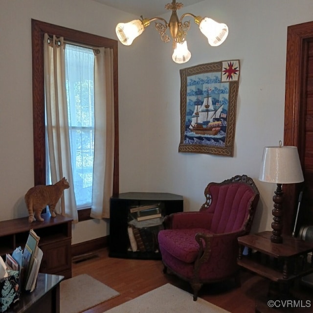 sitting room with hardwood / wood-style floors and a chandelier