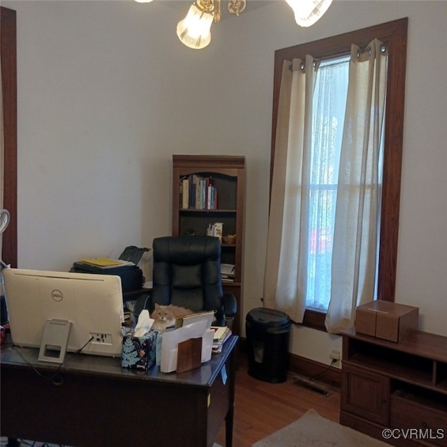 office with hardwood / wood-style flooring and a healthy amount of sunlight