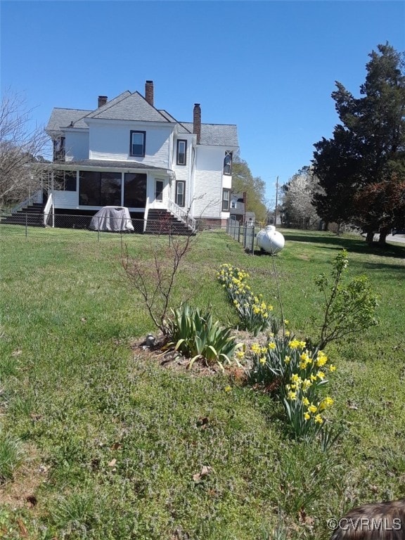 back of house with a sunroom, a yard, and a chimney