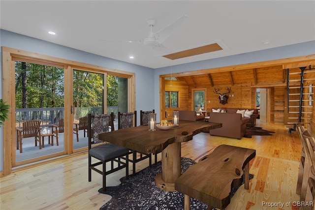 dining area with ceiling fan, wood walls, light wood-type flooring, and lofted ceiling with beams