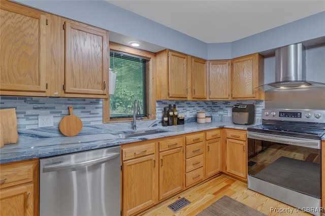 kitchen with light stone countertops, wall chimney exhaust hood, appliances with stainless steel finishes, and sink