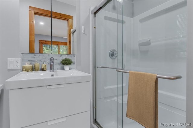 bathroom with a shower with door, vanity, and backsplash