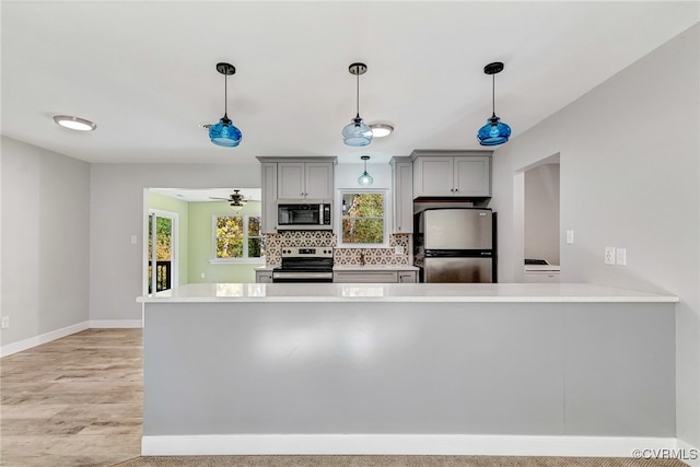 kitchen featuring gray cabinetry, ceiling fan, stainless steel appliances, kitchen peninsula, and pendant lighting