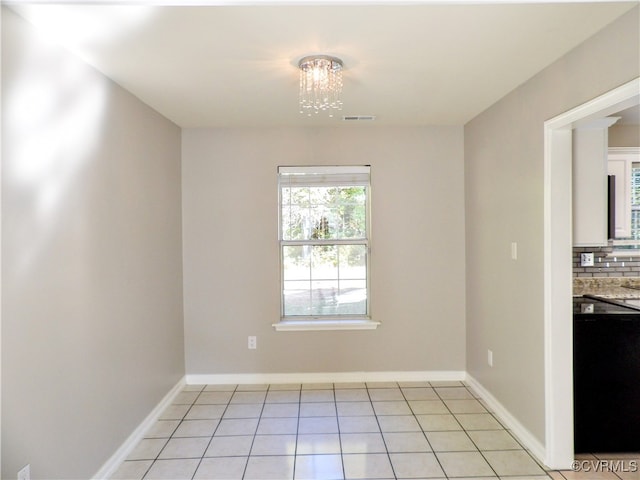 unfurnished dining area with a notable chandelier and light tile patterned flooring