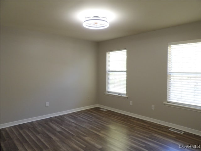 spare room with dark wood-type flooring and plenty of natural light