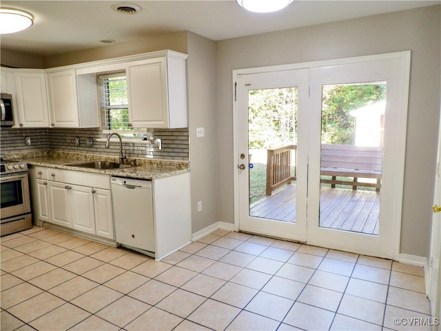 kitchen featuring decorative backsplash, sink, white cabinets, appliances with stainless steel finishes, and light stone counters