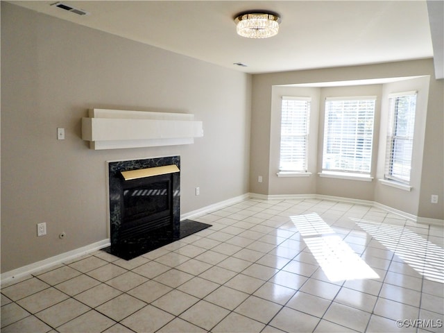 unfurnished living room with a notable chandelier, a fireplace, and light tile patterned floors