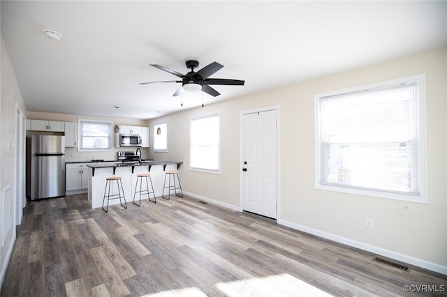 kitchen featuring white cabinetry, a healthy amount of sunlight, appliances with stainless steel finishes, and a breakfast bar area