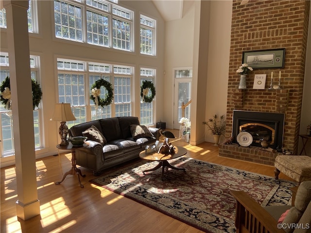 living room featuring light hardwood / wood-style flooring, a high ceiling, and a brick fireplace