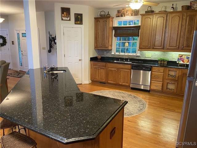 kitchen with sink, stainless steel appliances, light hardwood / wood-style flooring, and an island with sink