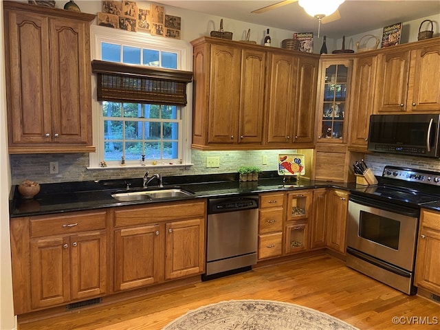 kitchen featuring light hardwood / wood-style flooring, backsplash, dark stone countertops, sink, and appliances with stainless steel finishes