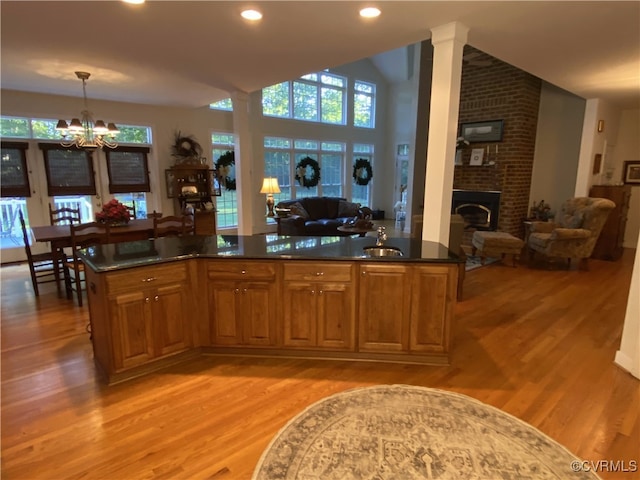 bar with sink, light wood-type flooring, a brick fireplace, hanging light fixtures, and a chandelier