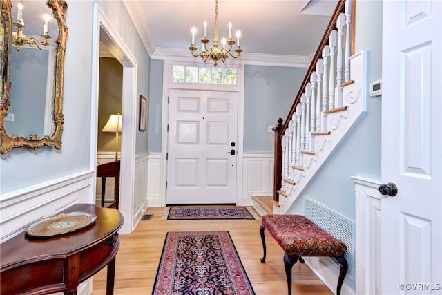 foyer featuring ornamental molding, light hardwood / wood-style floors, and a chandelier