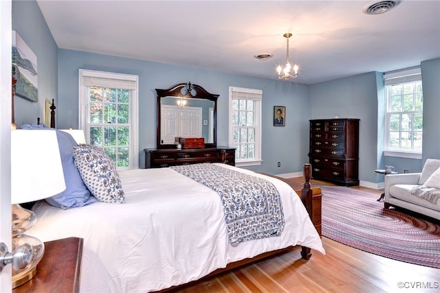 bedroom with wood-type flooring, multiple windows, and a notable chandelier