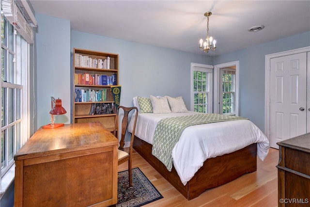 bedroom featuring light hardwood / wood-style floors, a chandelier, and a closet