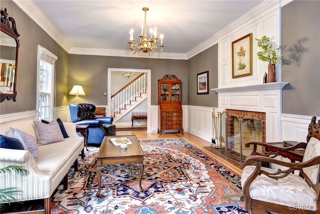 living room with a brick fireplace, light hardwood / wood-style flooring, a notable chandelier, and crown molding