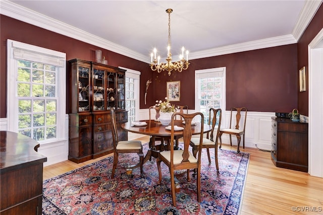 dining space with ornamental molding, light hardwood / wood-style floors, a notable chandelier, and a healthy amount of sunlight