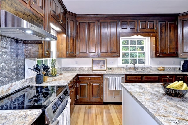 kitchen featuring stainless steel appliances, extractor fan, sink, light stone counters, and light hardwood / wood-style flooring