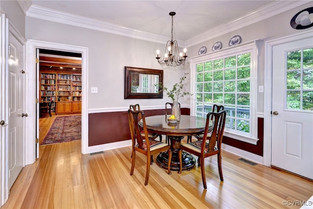 dining area with wood-type flooring, crown molding, and a notable chandelier