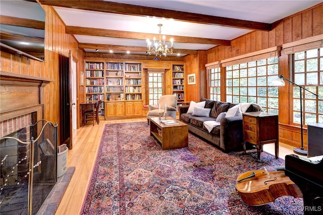 living room with wood walls, hardwood / wood-style flooring, beam ceiling, a fireplace, and a notable chandelier