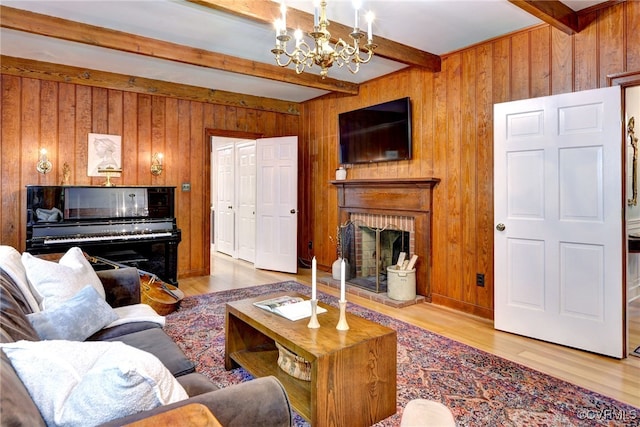 living room featuring a chandelier, beamed ceiling, wooden walls, and light hardwood / wood-style flooring