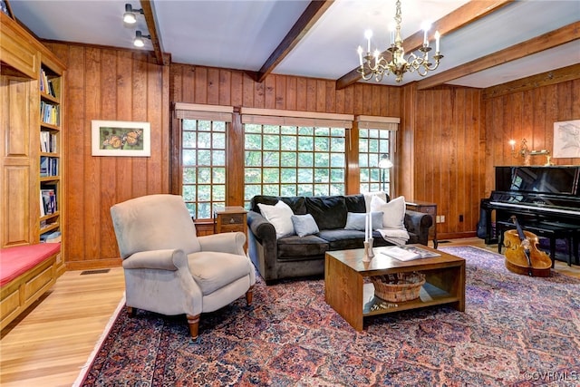 living room featuring wooden walls, hardwood / wood-style floors, a notable chandelier, and beam ceiling