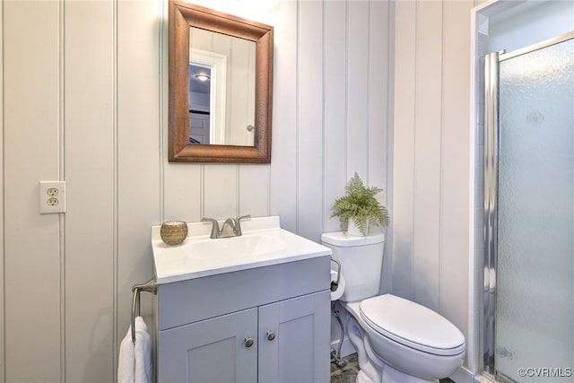 bathroom featuring toilet, vanity, and a shower with shower door