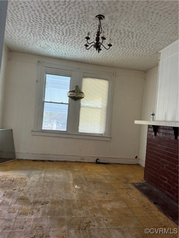 unfurnished dining area featuring an inviting chandelier and a textured ceiling