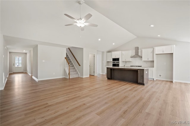 unfurnished living room featuring vaulted ceiling, light hardwood / wood-style flooring, and ceiling fan