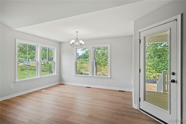 unfurnished dining area with a chandelier and light wood-type flooring