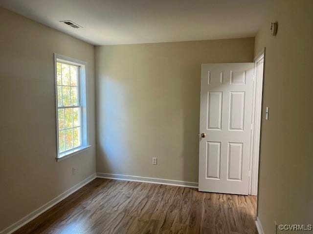 spare room with dark hardwood / wood-style flooring and a wealth of natural light