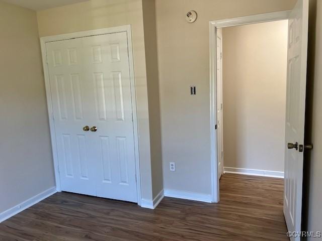 unfurnished bedroom featuring a closet and dark wood-type flooring