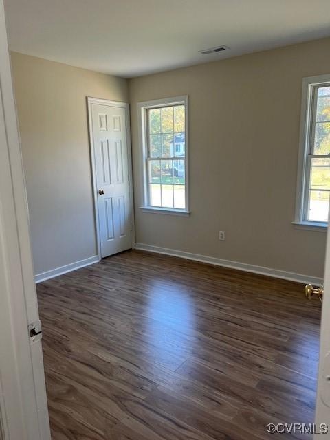 spare room featuring plenty of natural light and dark wood-type flooring