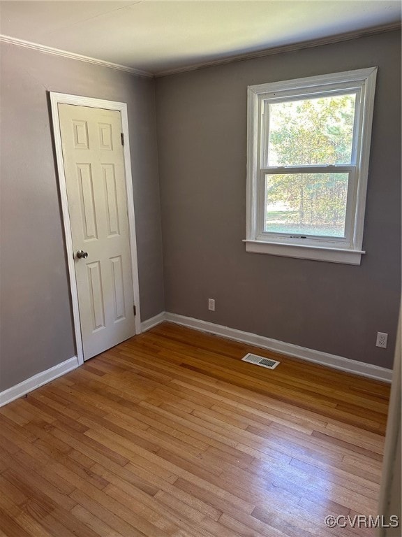 empty room featuring ornamental molding and light wood-type flooring