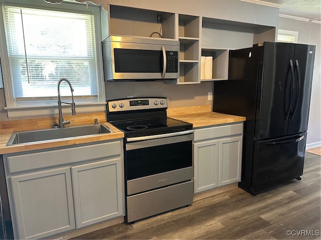 kitchen featuring hardwood / wood-style flooring, appliances with stainless steel finishes, sink, and ornamental molding