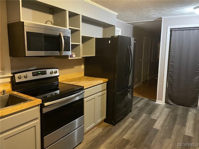 kitchen with dark hardwood / wood-style floors, stainless steel appliances, crown molding, butcher block countertops, and a textured ceiling