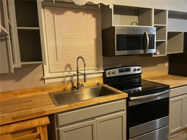 kitchen with sink, appliances with stainless steel finishes, and wood counters