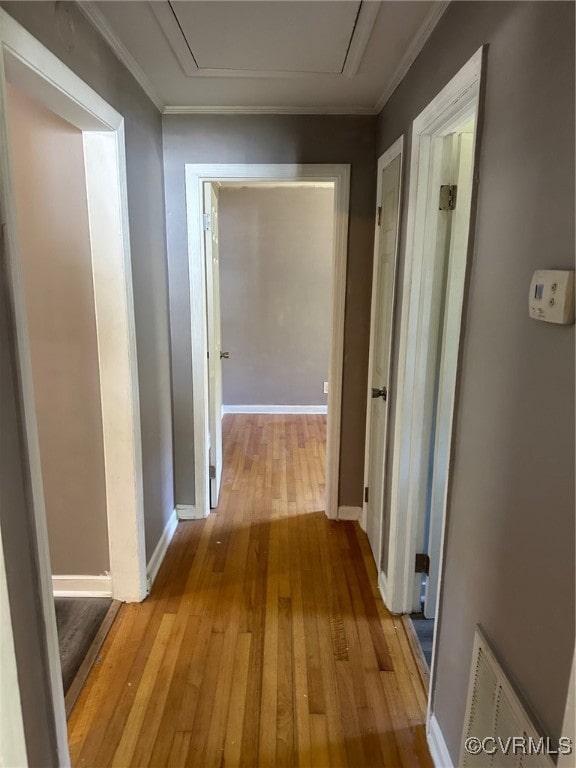 hall with ornamental molding and light hardwood / wood-style flooring