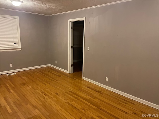 empty room with ornamental molding, a textured ceiling, and light hardwood / wood-style floors