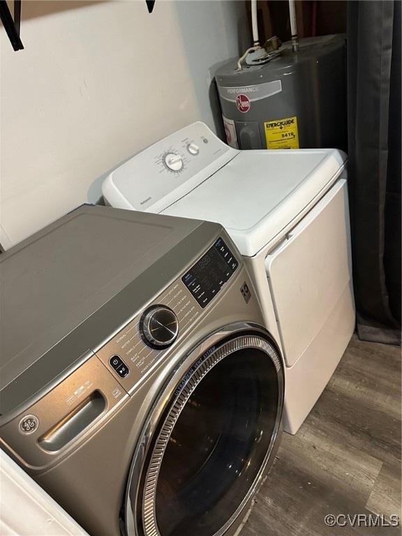 clothes washing area featuring electric water heater, washer and clothes dryer, and dark hardwood / wood-style flooring