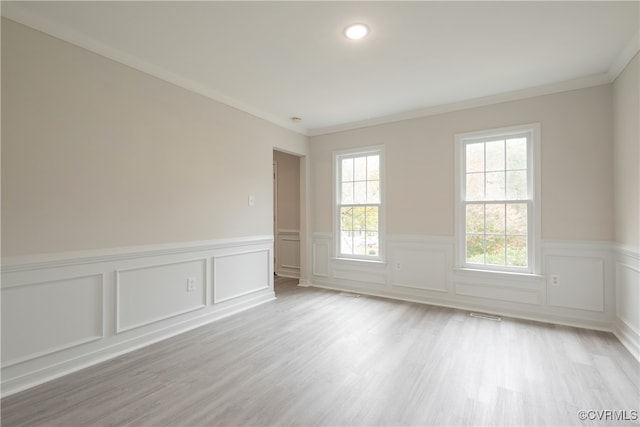 empty room with ornamental molding and light hardwood / wood-style flooring