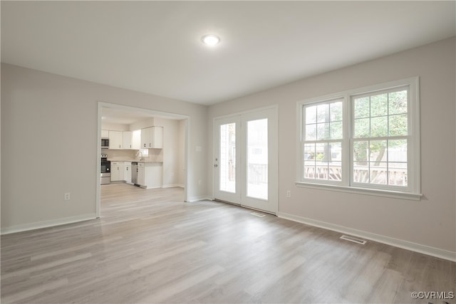 unfurnished living room with light hardwood / wood-style flooring and sink