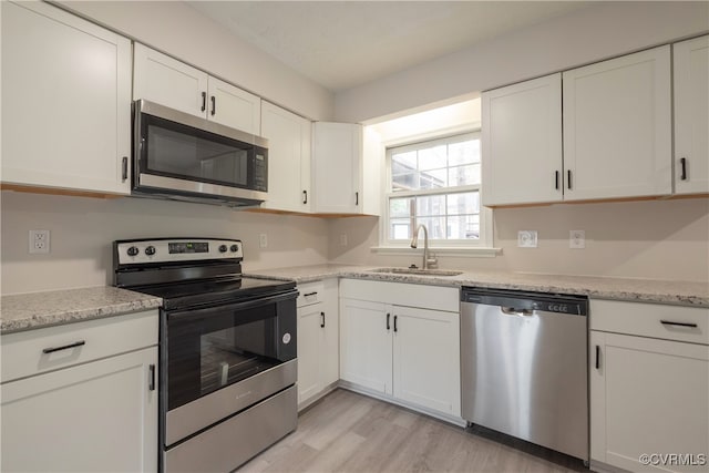 kitchen featuring appliances with stainless steel finishes, sink, light wood-type flooring, and white cabinets