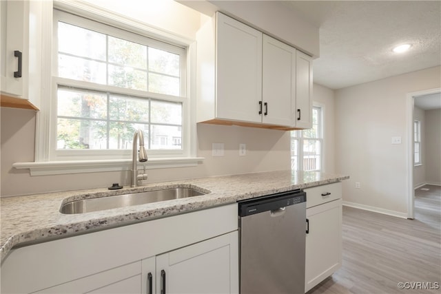 kitchen with dishwasher, light wood-type flooring, sink, white cabinetry, and light stone counters