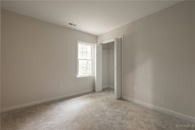 unfurnished bedroom featuring a closet and light carpet