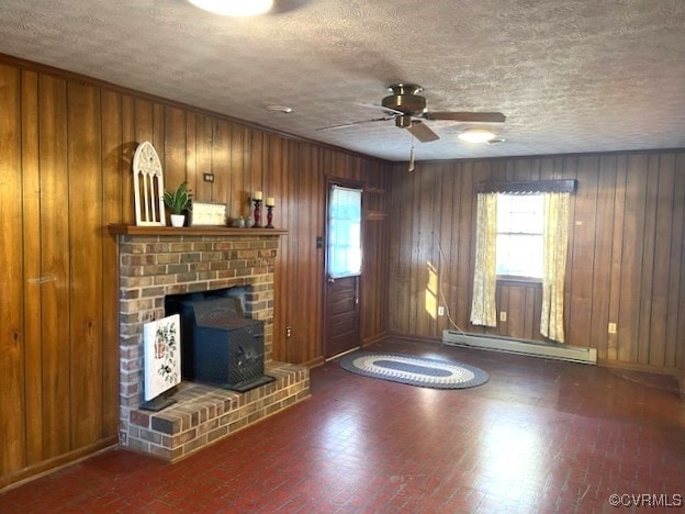 unfurnished living room with baseboard heating, wooden walls, plenty of natural light, and ceiling fan