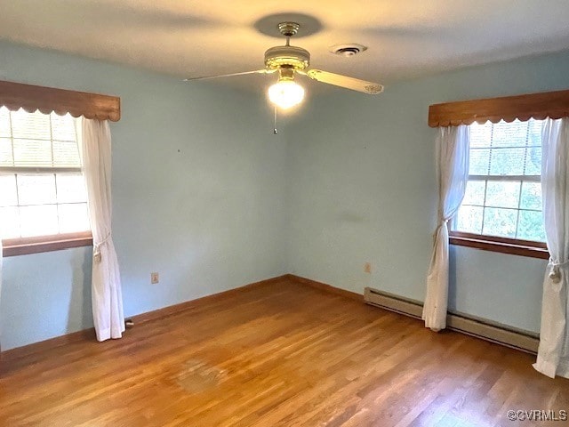 empty room featuring light hardwood / wood-style floors, a baseboard heating unit, and ceiling fan